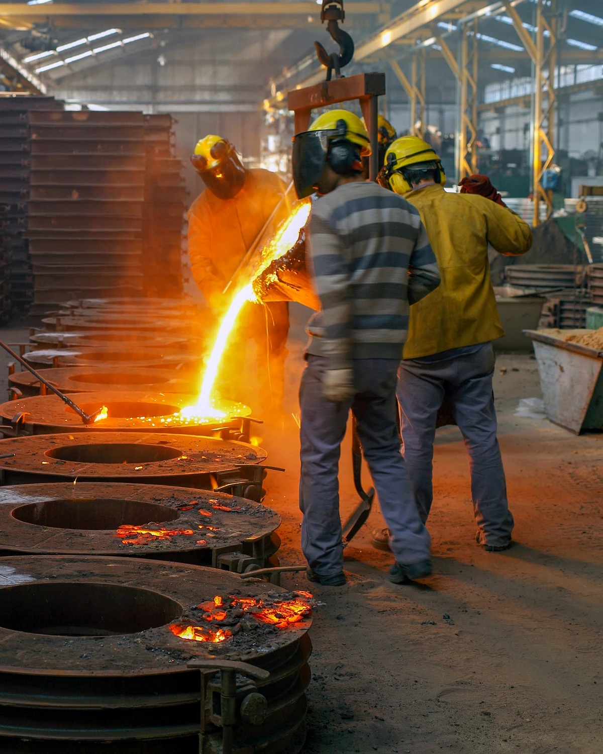 Foundry workers handling molten steel during casting